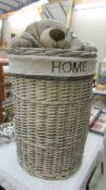 A wicker linen basket with soft toy dog lid, 46 cm diameter x 74 cm high.