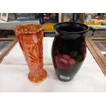 A glass vase in black and decorated with roses together with a pale orange pressed glass vase.