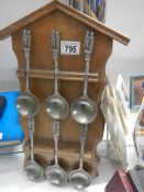 A set of six pewter spoons on rack.