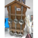 A set of six pewter spoons on rack.