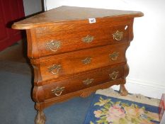 A Three drawer oak corner chest with serpentine front.
