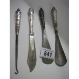 Three silver handled shoe horns and a button hook.