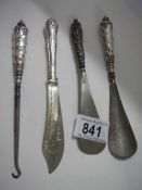 Three silver handled shoe horns and a button hook.