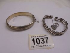 A silver gate bracelet with padlock and a silver bangle,