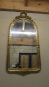 An arched top gilt framed bevel edged mirror. COLLECT ONLY.
