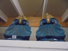 A pair of carved wood wall brackets in blue and gold.