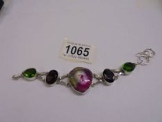 A silver stone set bracelet in tones of pink and green.