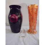 A glass vase in black and decorated with roses together with a pale orange pressed glass vase.