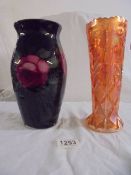A glass vase in black and decorated with roses together with a pale orange pressed glass vase.