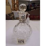 A heavy cut glass decanter with silver collar.