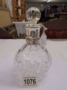 A heavy cut glass decanter with silver collar.