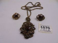 A decorative pendant with matching earrings.