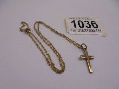 A 9ct gold cross on un-marked yellow metal chain.