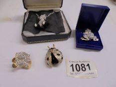 A sparkly panda pendant on chain, a teddy bear brooch, a frog brooch and a ladybird brooch.