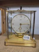A Kundo electro magnetic clock in glass and brass case, 6 jewels, in working order.