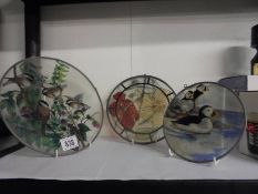 Three circular glass light catchers including two featuring birds.