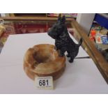 An art deco spelter scottie dog standing on an onyx ashtray.