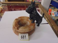 An art deco spelter scottie dog standing on an onyx ashtray.