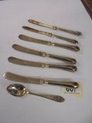 Six silver handled butter knives and a silver spoon.