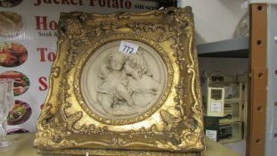 A cherub plaque in a gilded frame.