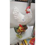 A large ceramic hen and a small cockerel.