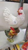 A large ceramic hen and a small cockerel.