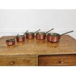 Set of five copper and brass sauce pans.