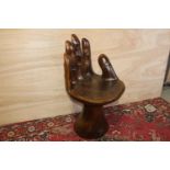 Wooden seat in the form of a hand with red painted nails