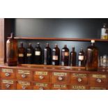 Ten brown glass chemist bottles with labels.