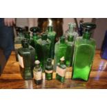 Thirteen green glass chemist bottles.