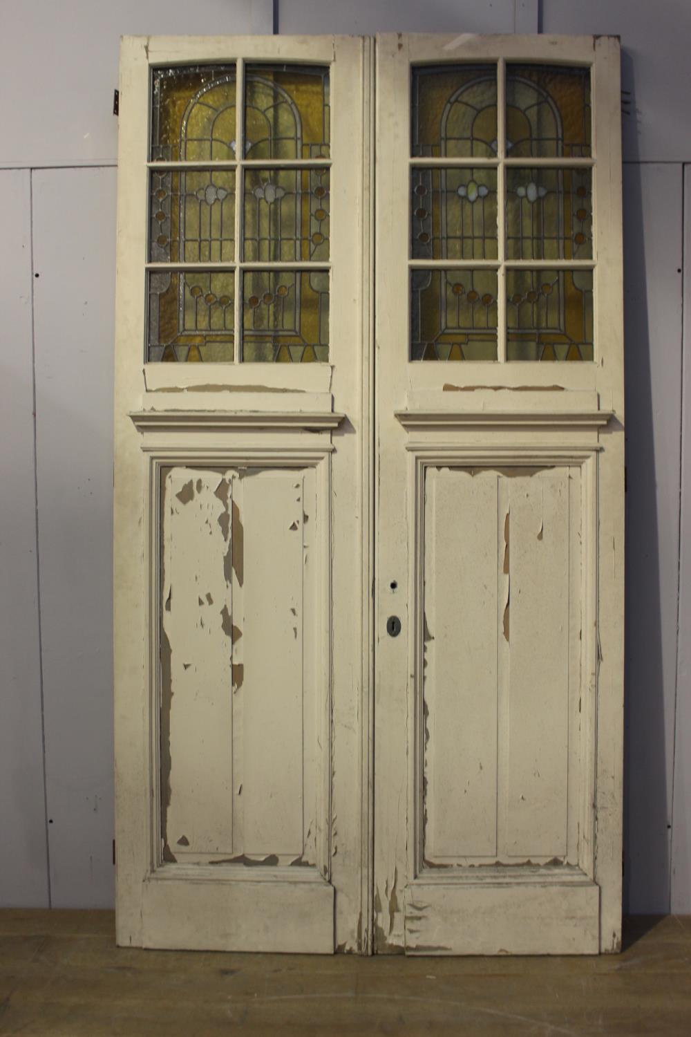 Pair of painted wooden doors with stain glass inserts.