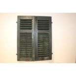 Pair of wooden window shutters with wrought iron hinges.