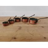 Set of five graduated copper and metal sauce pans.