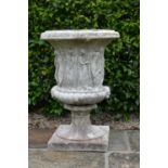 Large moulded stone urn with classical figure decoration on square base.