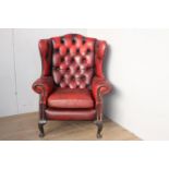 Red leather upholstered deep buttoned wing backed armchair