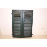 Pair of wooden window shutters with wrought iron hinges.