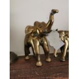Three brass models of elephants { 12cm H X 13cm W }. and a pair of brass candlesticks { 29cm H X 9cm