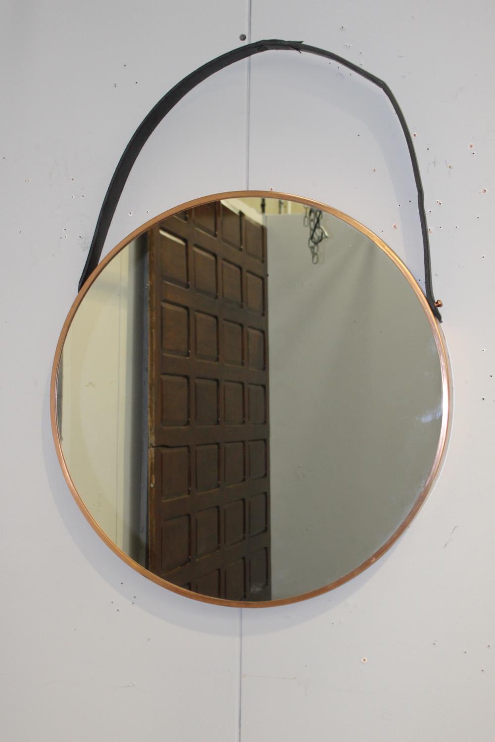 Copper framed mirror with hanging leather strap {76 cm Dia. X 5 cm D}.