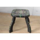 Black wooden milking stool with painted floral design {28 cm H x 30 cm W x 30 cm D}.