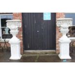 Pair of composition stone urns with ram's head decoration raised on square bases. {180 cm H x 70