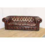 Deep buttoned leather upholstered three seater Chesterfield sofa {72 cm H x 210 cm W x 98 cm D}.