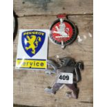 Two car badges and Peugeot enamel advertising sign.