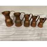 Set of four graduated copper jugs.