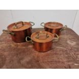 A set of three copper and brass lidded saucepans {14cm H x 26cm W x 18cm D Largest / 10cm H x 21cm W