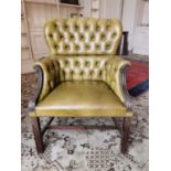 Deep buttoned leather upholstered wing backed armchair raised on squared reeded legs, in the