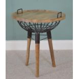 Coffee table with wooden tray top above a storage basket raised on three tapered legs, in the