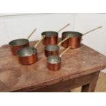 A set of six graduated copper and brass saucepans {15cm H x 35cm W x 18 D Largest - 8cm H x 18cm W x