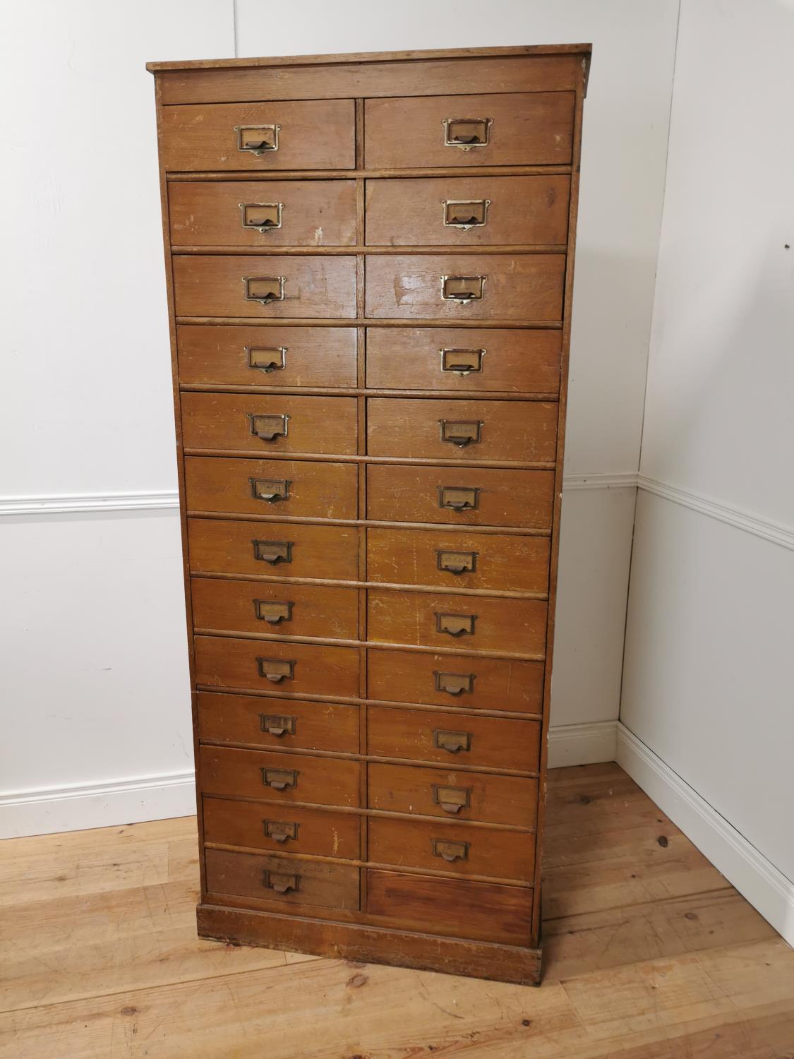 Early 20th. C. painted pine bank of twenty five short drawers with original handles, raised on