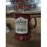 Lang’s Supreme Scotch Whiskey ceramic advertising water jug. {14 cm H x 17 cm W x 10 cm D}.