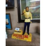 Composition advertising figure Duquesne Pilsener The Finest Beer in Town. {28 cm H x 18 cm W x 8